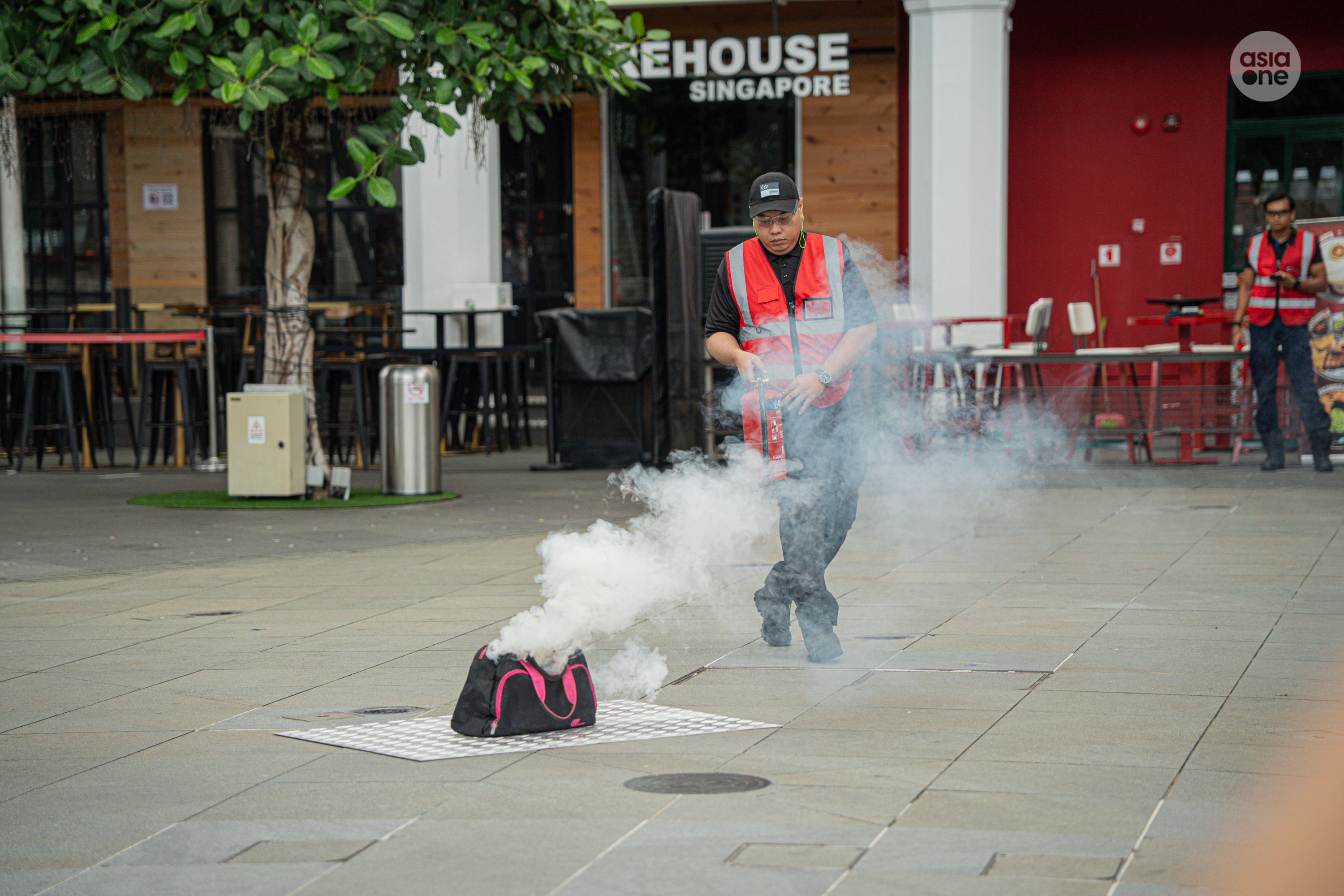 A bag placed outside a live music bar at CQ @ Clarke Quay starts emitting smoke. CQ's Cert team arrives with a fire extinguisher.