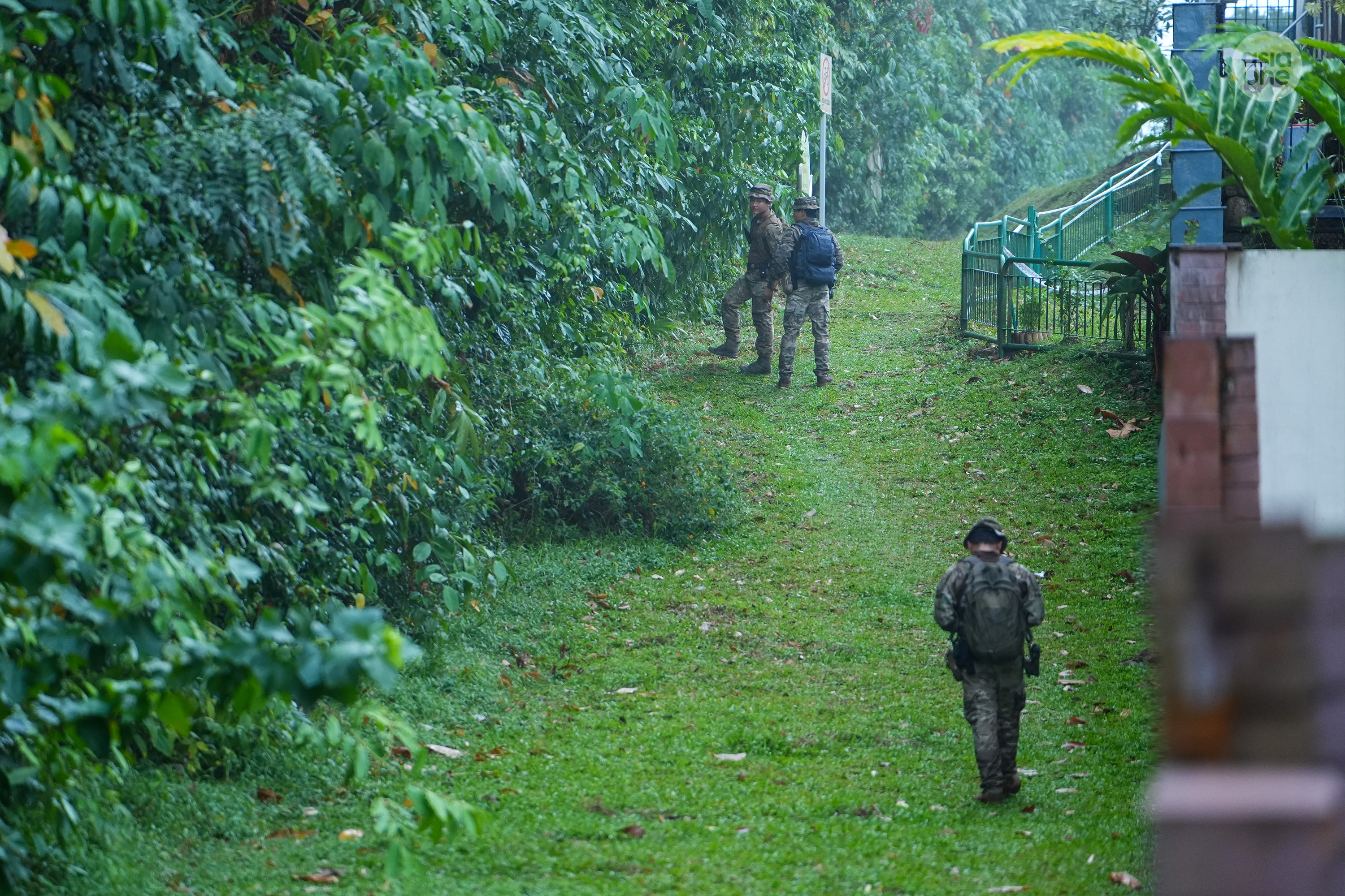 Gurkha officers from the Singapore Police Force entering the forested area bordering the backyards of private residential properties at Soo Chow Drive.